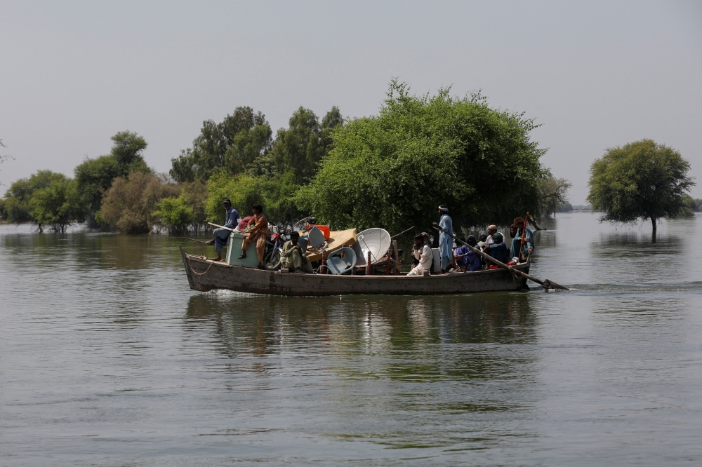 A family with their belongings travel in a boat, following rains and floods during the monsoon season in Karampur village in Sehwan, Pakistan September 15, 2022. REUTERS/Akhtar Soomro