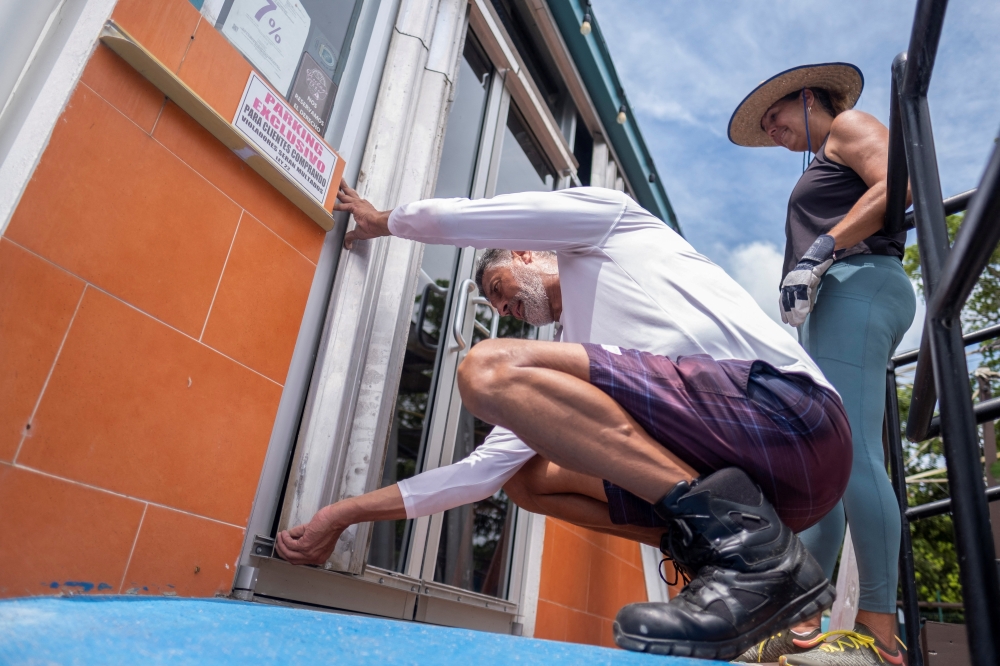 Jose Ortiz installs metal storm shutters in his restaurant in preparation for the arrival of tropical storm Fiona and its heavy rains in Lajas, Puerto Rico September 17, 2022. Reuters/Ricardo Arduengo
 