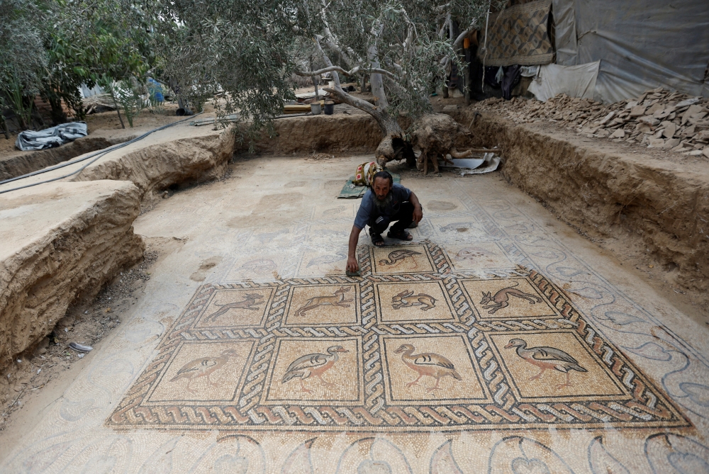 Palestinian farmer Salman al-Nabahin cleans a mosaic floor he discovered at his farm and which dates back to the Byzantine era, according to officials, in the central Gaza Strip, on September 18, 2022. (REUTERS/Ibraheem Abu Mustafa)