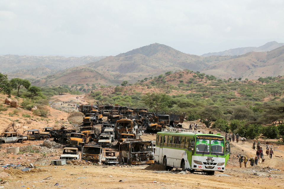 Villagers return from a market to Yechila town in south central Tigray walking past scores of burned vehicles, in Tigray, Ethiopia, on July 10, 2021. File Photo / Reuters
