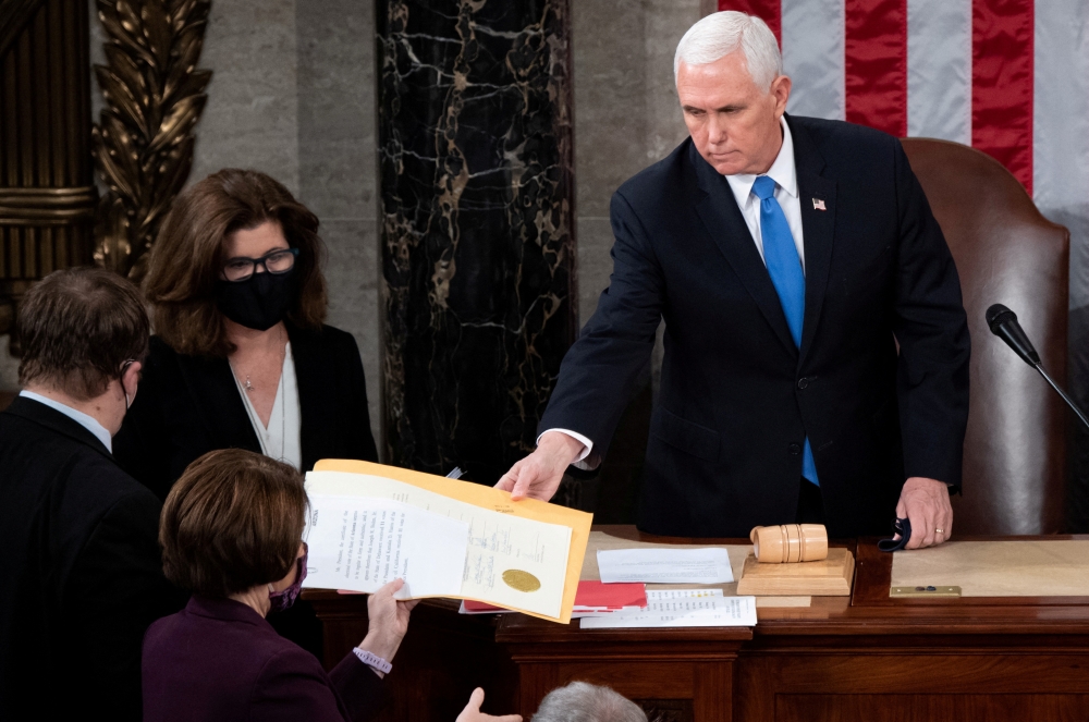 US Vice President Mike Pence hands the electoral certificate from the state of Arizona to US Senator Amy Klobuchar, Democrat of Minnesota, as he presides over a joint session of Congress to certify the 2020 election results on Capitol Hill in Washington on January 6, 2021. File Photo / Reuters
