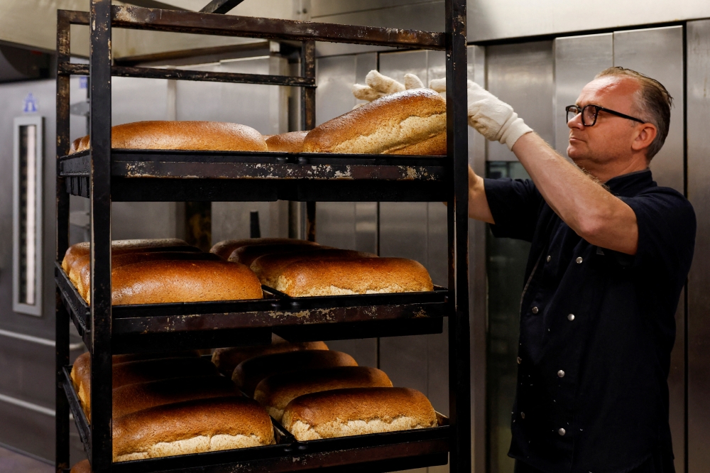Owner Dennis Toebast takes the bread out of the oven at his bakery in Hoevelaken, Netherlands September 21, 2022. Reuters/Piroschka van de Wouw
 