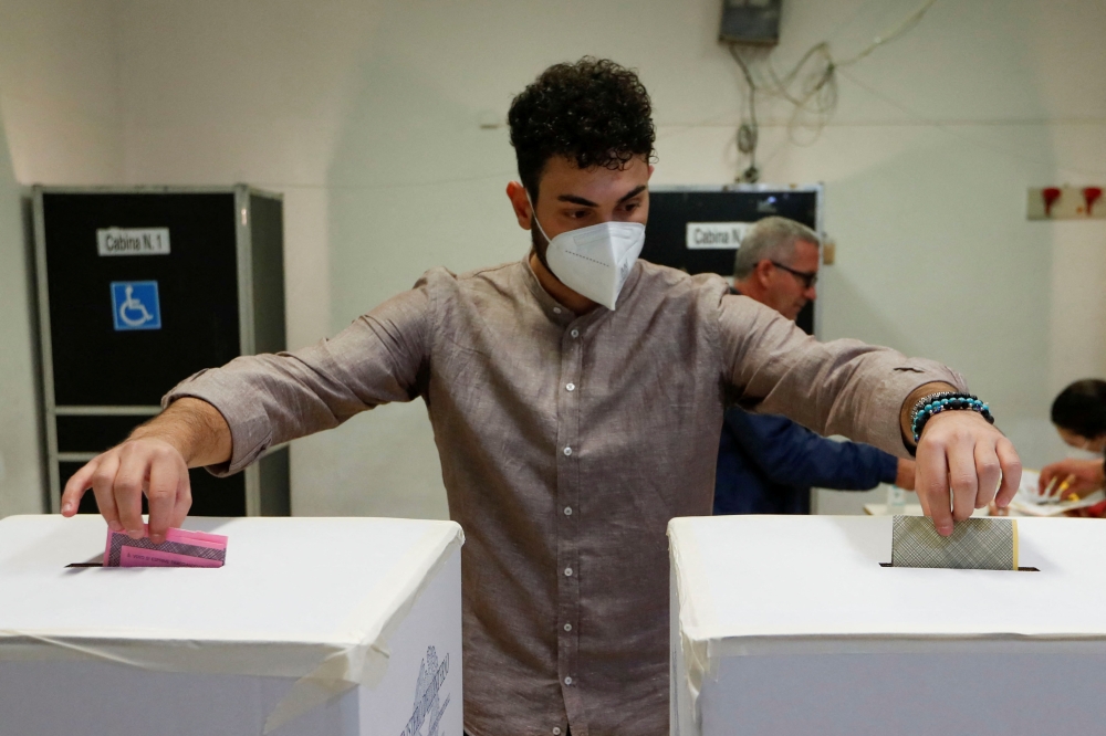 A man drops ballots into boxes at a polling station during the snap election, in Rome, Italy, September 25, 2022. Reuters/Remo Casilli
