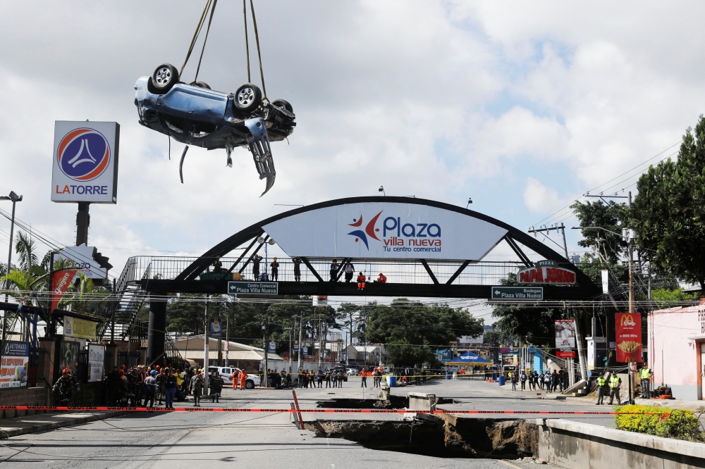 A vehicle is put out of a sinkhole opened by the rains, in Villa Nueva, Guatemala September 25, 2022. (REUTERS/Luis Echeverria)