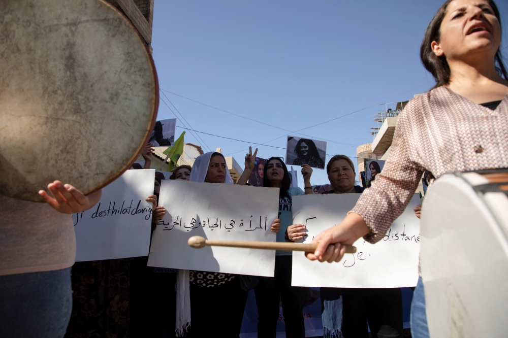 Women carry banners and play instruments during a protest over the death of 22-year-old Kurdish woman Mahsa Amini in Iran, in the Kurdish-controlled city of Qamishli, northeastern Syria on September 26, 2022.   REUTERS/Orhan Qereman