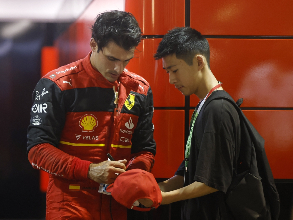 Ferrari's Carlos Sainz Jr. signs a cap for a fan after the second practice session for the Singapore Grand Prix in Marina Bay Street Circuit, Singapore, on September 30, 2022. (REUTERS/Edgar Su)