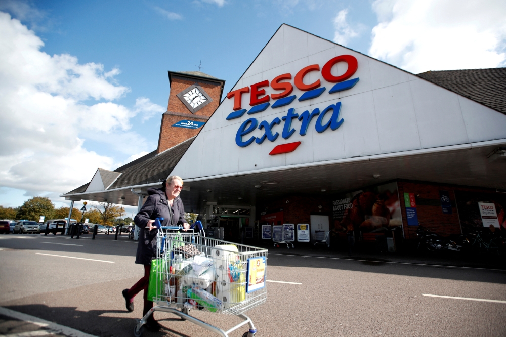 File photo of a woman with a shopping cart as she walks past a Tesco supermarket in Hatfield, Britain October 6, 2020. Reuters /Peter Cziborra/File Photo