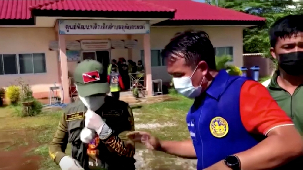 Officials and authorities guard the gate of daycare centre as people wait, after a mass shooting, in Uthai Sawan, Nong Bua Lamphu Province, Thailand in this screengrab taken from video on October 6, 2022. TPBS/Reuters
