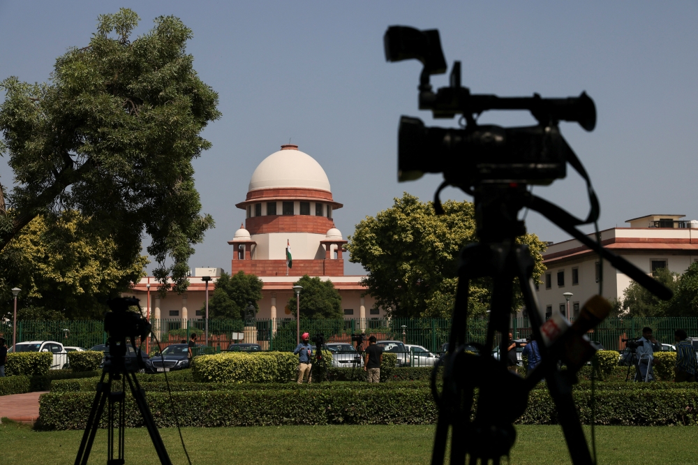 Members of media speak in front of cameras after a panel of the Supreme Court said it was divided on a decision to allow hijabs in classrooms, outside the premises of the court in New Delhi, India, October 13, 2022. (REUTERS/Anushree Fadnavis)