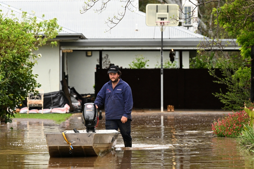 A man pushes a boat as floodwaters inundate a Victorian residential area amidst evacuation orders in Rochester, Australia, October 14, 2022. AAP Image/James Ross via REUTERS