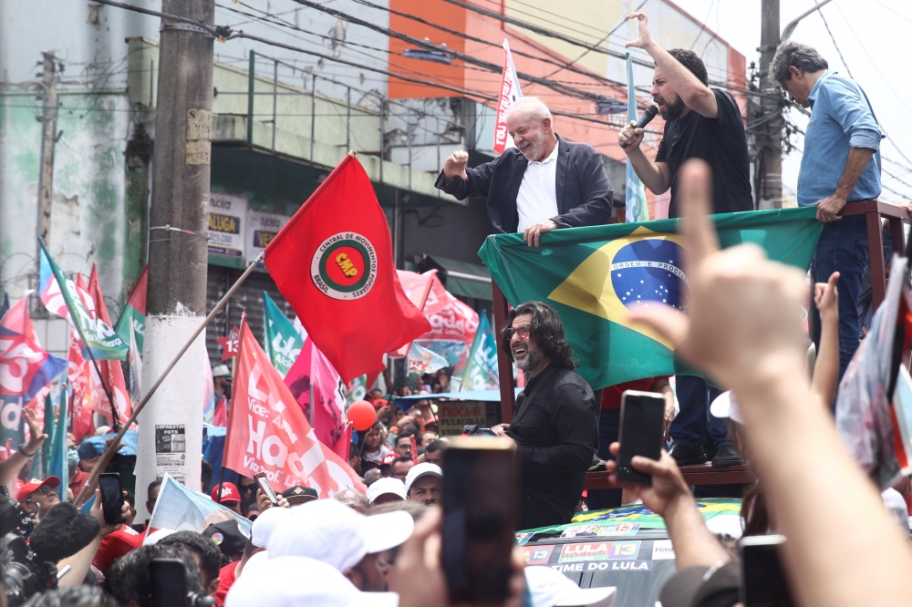 Former Brazil's President and current presidential candidate Luiz Inacio Lula da Silva and Sao Paulo Governor candidate Fernando Haddad greet supporters during a march in Sao Paulo, Brazil, October 17, 2022. (REUTERS/Carla Carniel)