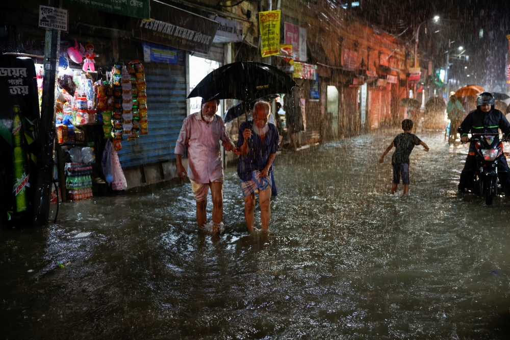 People wade through a flooded street amid continuous rain before the Cyclone Sitrang hits the country in Dhaka, Bangladesh, October 24, 2022. REUTERS .
