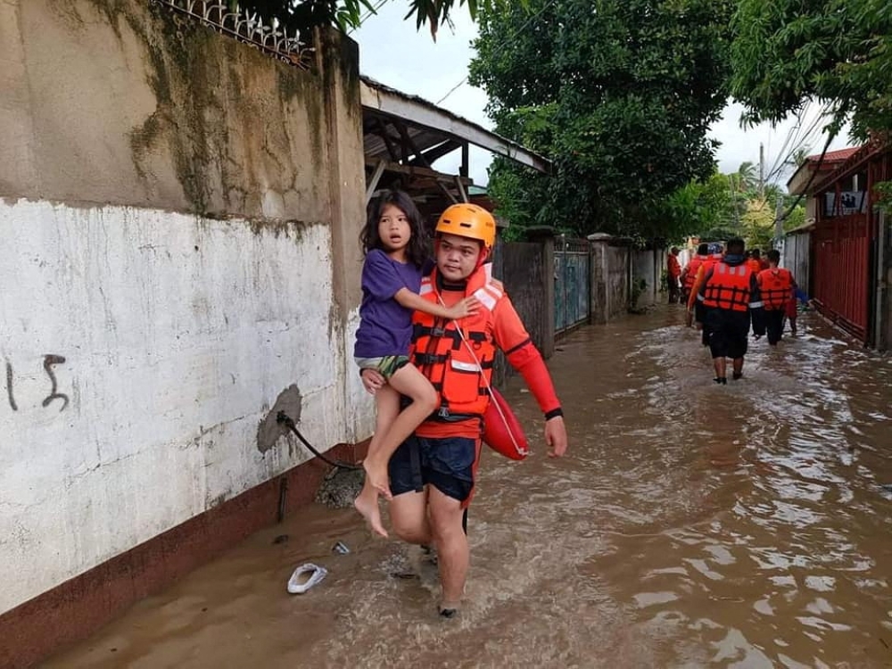 A Philippine Coast Guard (PCG) rescuer evacuates a child following flooding due to Tropical Storm Nalgae, in Zamboanga, Philippines, October 29, 2022. Philippine Coast Guard/Handout via Reuters