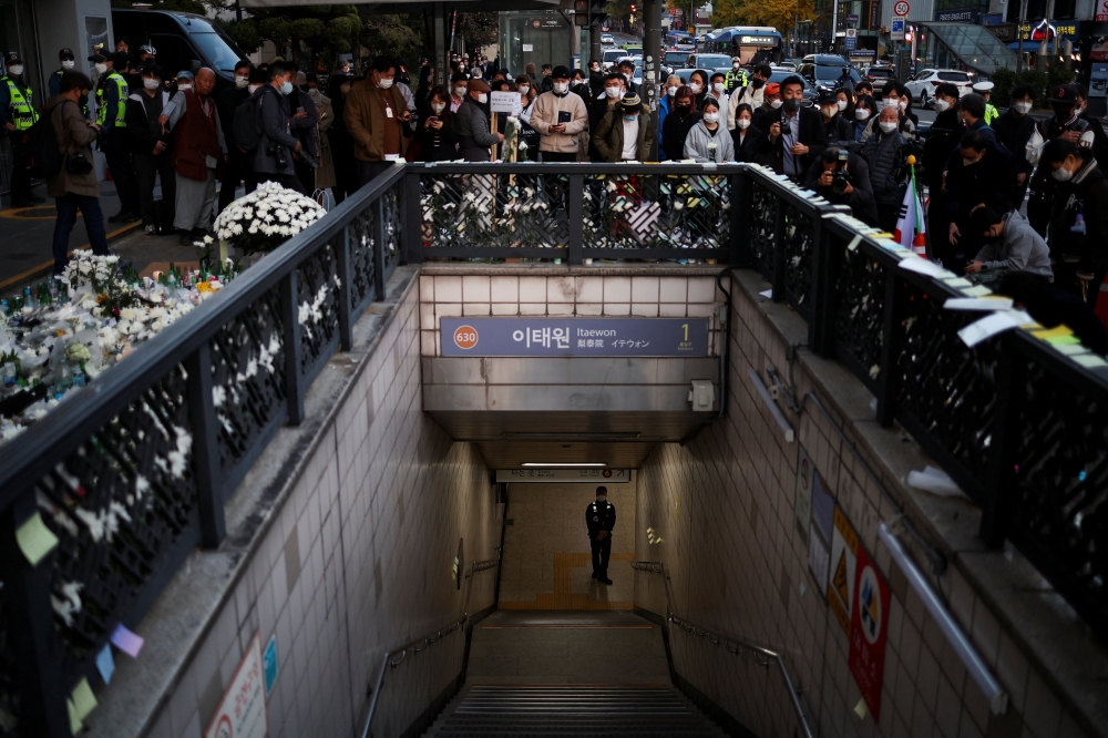 A police officer stands guard at the exit of a subway station as people gather to pay their respects following a crowd crush that happened during Halloween festivities, in Seoul, South Korea, November 1, 2022. REUTERS/Kim Hong-Ji