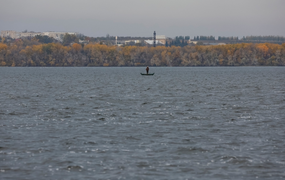 A fisherman stands in a boat on the Dnipro river near the town of Nova Kakhovka, Russian-controlled Ukraine, October 30, 2022. (REUTERS/Alexander Ermochenko)