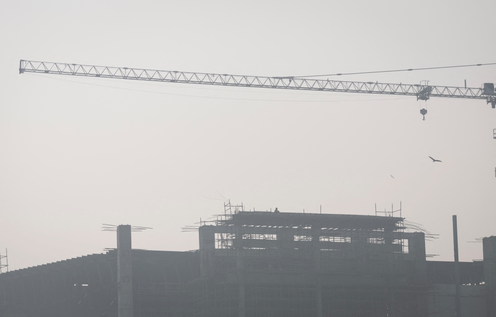 A labourer sits on top of an under-construction building on a smoggy morning in New Delhi, India November 2, 2022. REUTERS/Adnan Abidi