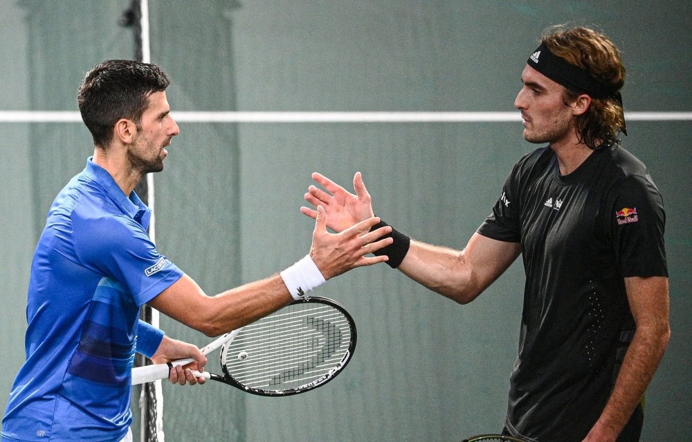 Serbia's Novak Djokovic (left) shakes hands with Greece's Stefanos Tsitsipas after winning at the end of their men's singles semi-final tennis match on day 6 of the ATP World Tour Masters 1000 - Paris Masters (Paris Bercy) - indoor tennis tournament at The AccorHotels Arena in Paris on November 5, 2022. (Photo by Christophe ARCHAMBAULT / AFP)