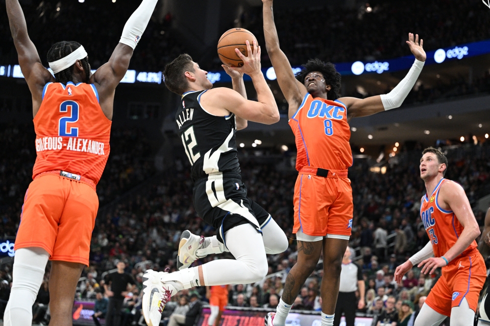 Milwaukee Bucks guard Grayson Allen (12) takes a shot against Oklahoma City Thunder guard Shai Gilgeous-Alexander (2), left and forward Jalen Williams (8) in the second quarter at Fiserv Forum. Michael McLoone