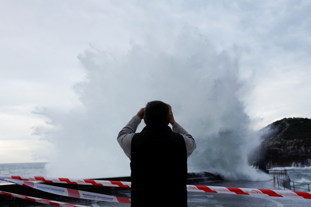 A man takes photographs as large waves crash against a breakwater in Lekeitio, Spain, November 7, 2022. (REUTERS/Vincent West)