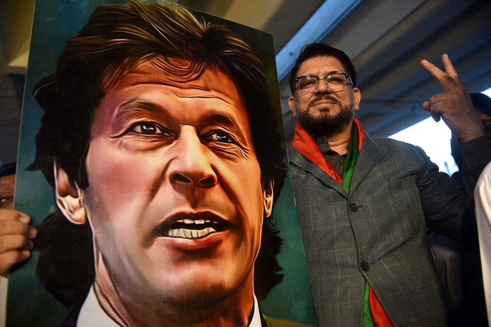A supporter of Pakistan's former prime minister Imran Khan, gestures while holding Khan's portrait during a protest against the assassination attempt on him, in Karachi on November 6, 2022. (AFP/Rizwan Tabassum)