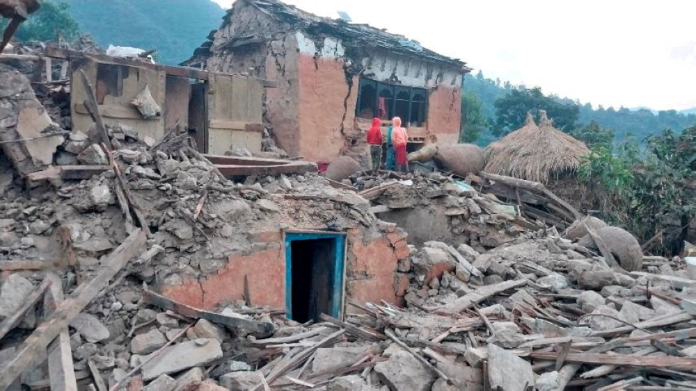 People stand outside the ruins of collapsed houses after an earthquake struck early Wednesday, in the western district of Doti, Nepal November 9, 2022. Nepal Army/Handout via Reuters