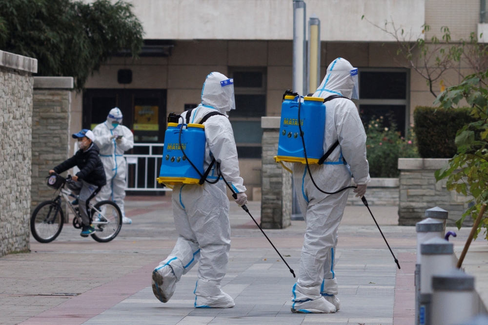 Pandemic prevention workers in protective suits spray disinfectant in a residential compound that was placed under lockdown as outbreaks of coronavirus disease (COVID-19) continue in Beijing, China November 9, 2022. REUTERS/Thomas Peter