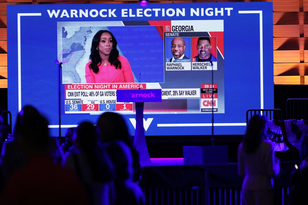 Political news is seen on a screen during the Election night party for Democratic Senate Candidate Raphael Warnock (D-GA) at Atlanta Marriott Marquis on November 08, 2022 in Atlanta, Georgia. Sen. Warnock is in a very tight race with Republican challenger Herschel Walker. If neither candidate receives 50 percent plus one vote needed, they will head to a runoff in December. Michael M. Santiago/Getty Images/AFP
 