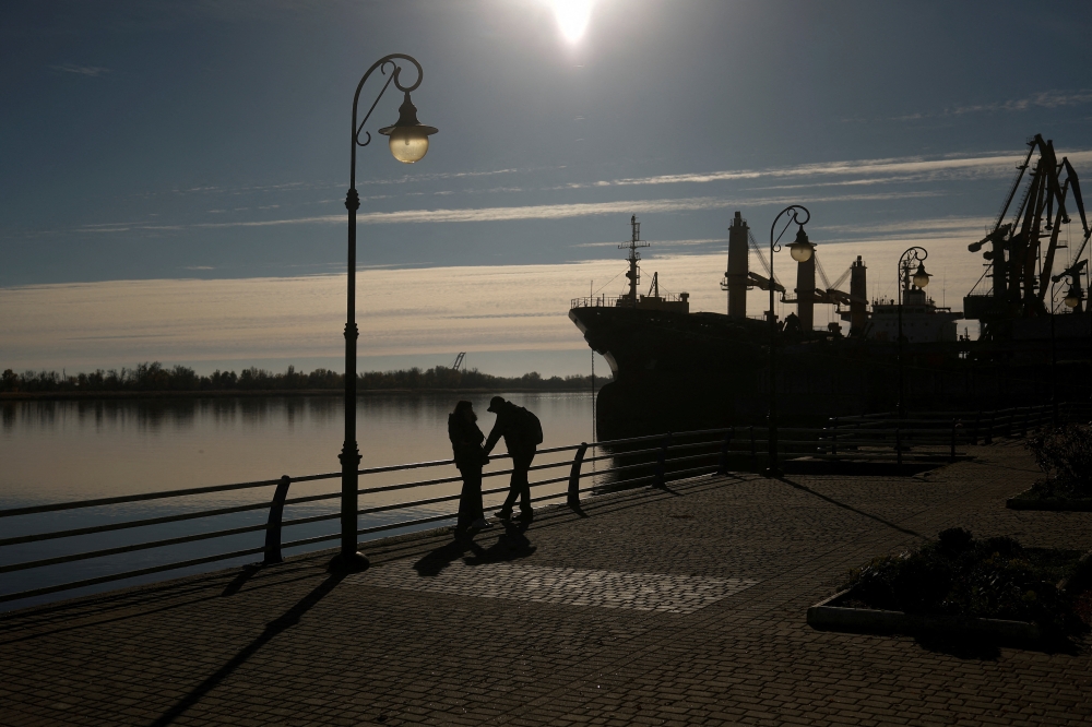 People speak with their smartphones on a bank of the Dnipro river after Russia's retreat from Kherson, in Kherson, Ukraine November 14, 2022. REUTERS/Valentyn Ogirenko