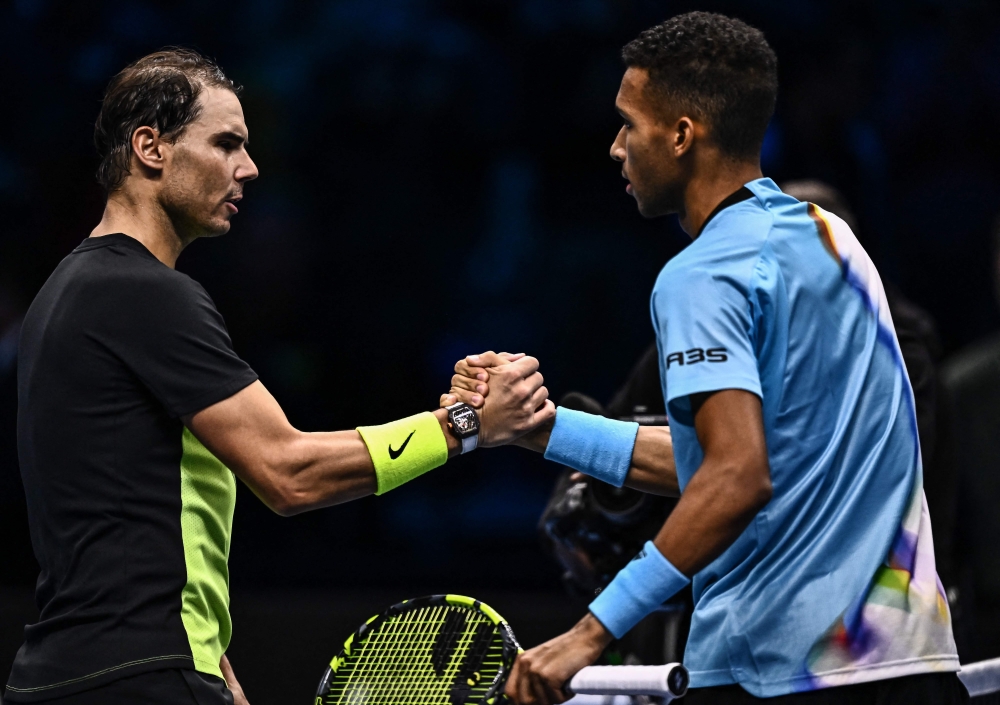 Spain's Rafael Nadal (left) and Canada's Felix Auger-Aliassime tap hands after Auger-Aliassime won their round-robin match on November 15, 2022 at the ATP Finals tennis tournament in Turin. (Photo by Marco BERTORELLO / AFP)