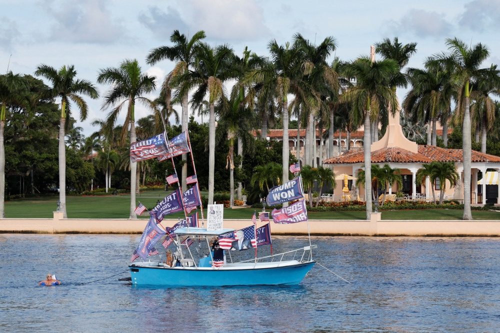 Supporters sail their boat in Lake Worth Lagoon behind former US President Donald Trump's Mar-a-Lago estate where he says he will make a 