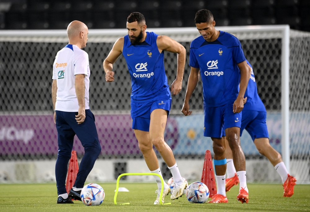 France's forward Karim Benzema (center) and France's defender Raphael Varane takes part in a training session next to France's head coach Guy Stephan (left) at the Jassim-bin-Hamad Stadium in Doha on November 19, 2022, ahead of the Qatar 2022 World Cup football tournament. (Photo by FRANCK FIFE / AFP)