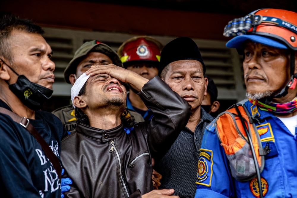 Ahmad Ashikin (2L), father of seven-year-old Indonesian girl Ashika Nur Fauziah, reacts after rescue personnels found her dead under the rubble at Cugenang village, in Cianjur, on November 25, 2022. Photo by Mas Agung Wilis / AFP