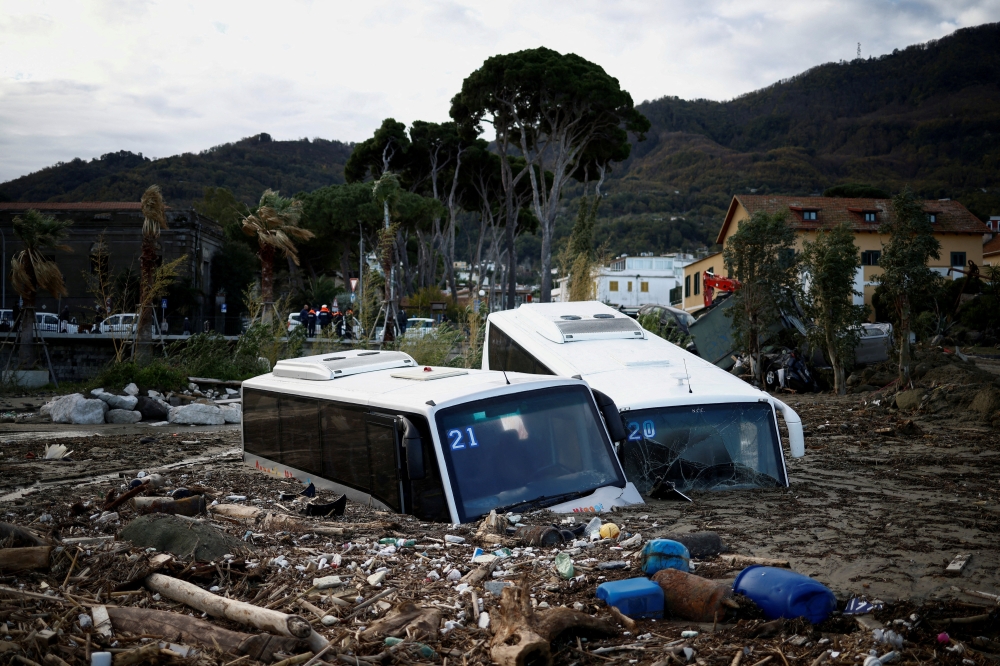 Damaged buses lie amongst debris following a landslide on the Italian holiday island of Ischia, Italy, November 27, 2022. (REUTERS/Guglielmo Mangiapane)