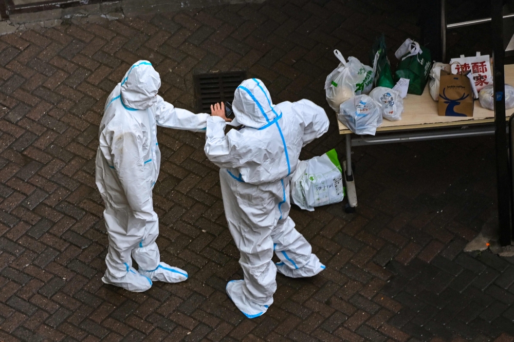 Security guards are seen at the entrance of a compound under Covid-19 lockdown in the Jing'an district in Shanghai on December 3, 2022. (Photo by Hector RETAMAL / AFP)