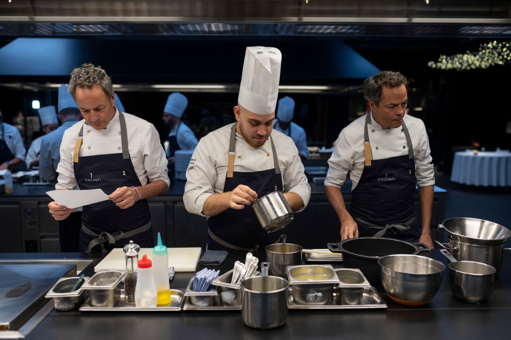 In this photograph taken on December 1, 2022 Spanish twin chefs, Javier (R) and Sergio (L) Torres prepare some meals in the kitchen of their restaurant 'Cocina Hermanos Torres' after receiving the distinction of three-stars from the Michelin guide, in Barcelona. Photo by Josep LAGO / AFP