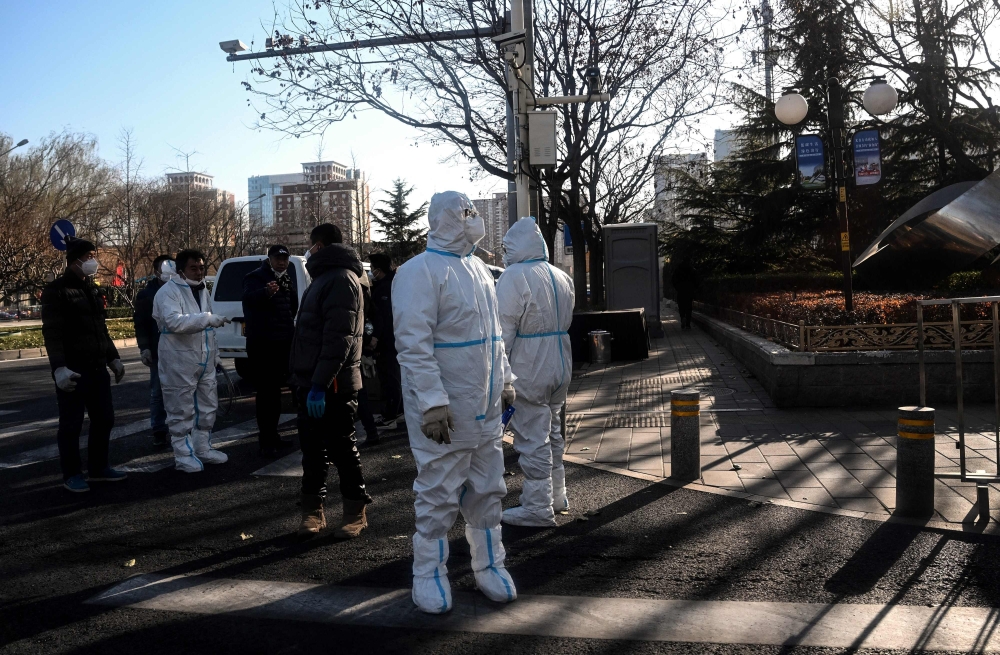People wear personal protective equipment (PPE) along a street in Beijing on December 5, 2022. (Photo by Noel Celis / AFP)