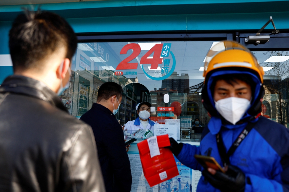 People line up to buy fever and cold medicine as a delivery worker picks up an order at a pharmacy, amid the coronavirus disease (COVID-19) outbreak, in Beijing, China December 6, 2022. Reuters/Tingshu Wang