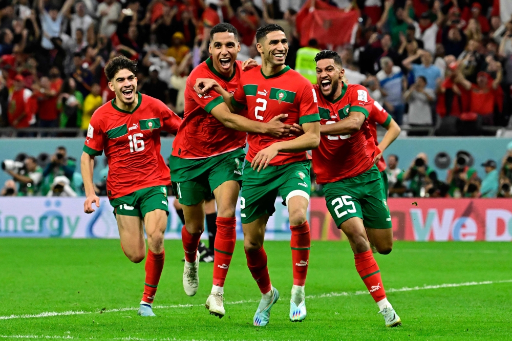 Morocco's defender #02 Achraf Hakimi (C) celebrates with teammates after converting the last penalty during the penalty shoot-out to win the Qatar 2022 World Cup round of 16 football match between Morocco and Spain at the Education City Stadium in Al-Rayyan, west of Doha on December 6, 2022. (Photo by JAVIER SORIANO / AFP)