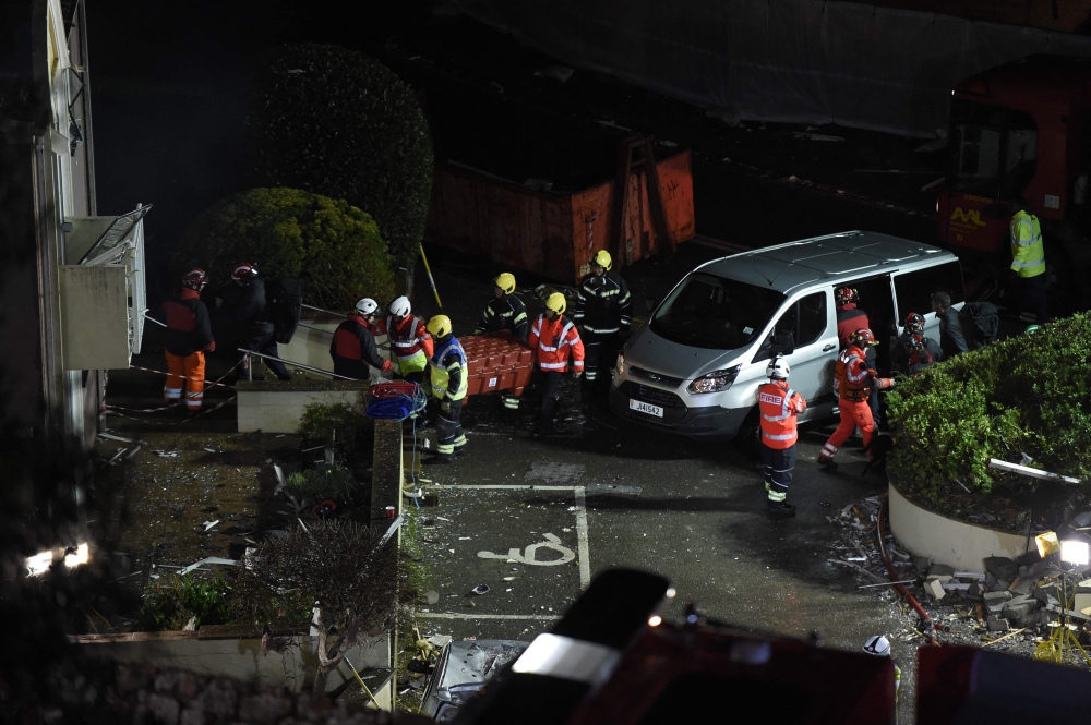 Fire crews mobilised work in the rubble of a low-rise apartment block after an explosion on December 10, 2022 in Saint-Helier, Jersey Island, killed three people and several others are missing, authorities said. (Photo by Sebastien SALOM-GOMIS / AFP)