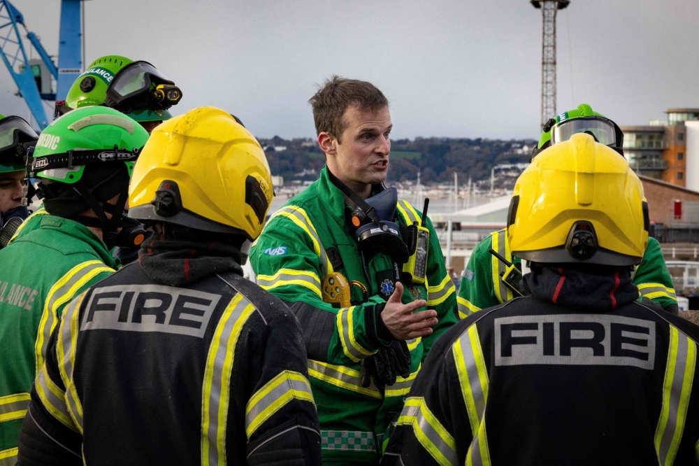 This handout picture obtained on December 11, 2022 from the Government of Jersey shows fire crews speaking next to the rubble of a low-rise apartment building after an explosion, in the Channel island's port capital Saint Helier. (Photo by Government of Jersey. / AFP) 