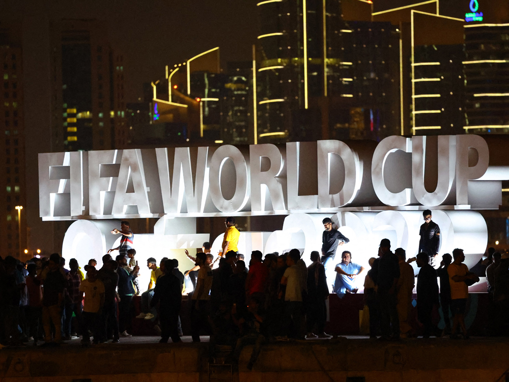 People take photographs in front of an installation at the Doha Corniche. 