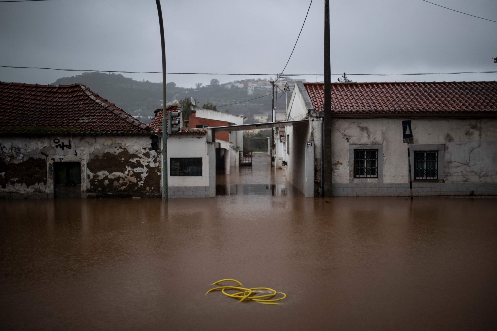 A hose is pictured in the middle of a flooded street, in Frielas, on the outskirts of Lisbon, following heavy rain on December 13, 2022. (Photo by CARLOS COSTA / AFP)