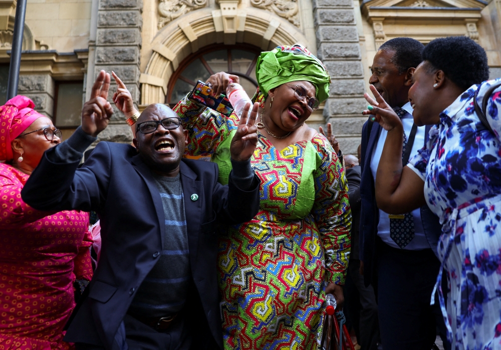 African National Congress parliament members celebrate after President Cyril Ramaphosa survives an impeachment vote during South Africa's parliament debate on a report by a panel of experts who found that President Cyril Ramaphosa may have violated his oath of office, following allegations that large sums of foreign currency were hidden at his private game farm, in Cape Town, South Africa, on December 13, 2022. REUTERS/Esa Alexander
