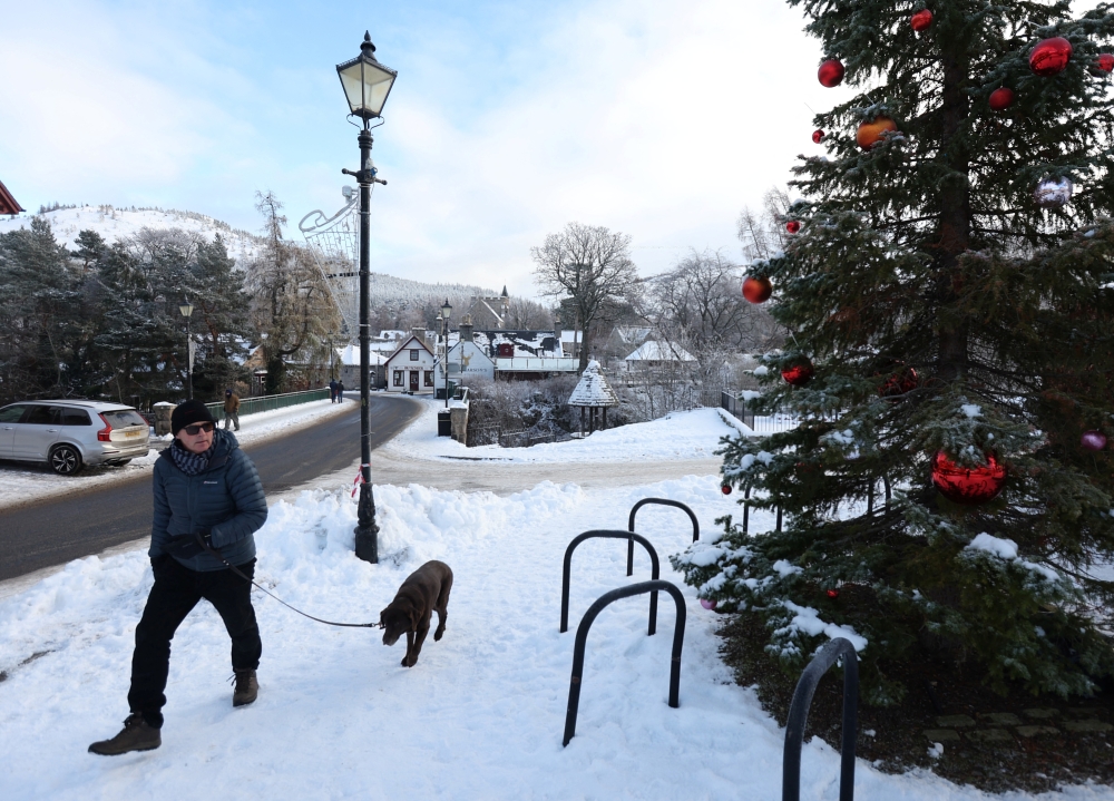 A man walks a dog in Braemar, Scotland, Britain December 13, 2022. REUTERS/Russell Cheyne