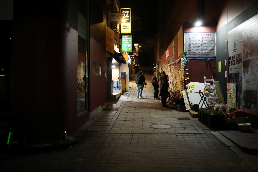 People read condolences messages attached to the wall of a narrow alley of Itaewon where the deadly Halloween crush that killed more than 150 in October happened, in Seoul, South Korea, December 18, 2022. REUTERS/Kim Hong-Ji
 