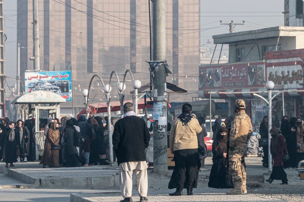 Afghan female university students stop by Taliban security personnel stand next to a private university in Kabul on December 21, 2022. Photo by Wakil Kohsar / AFP
