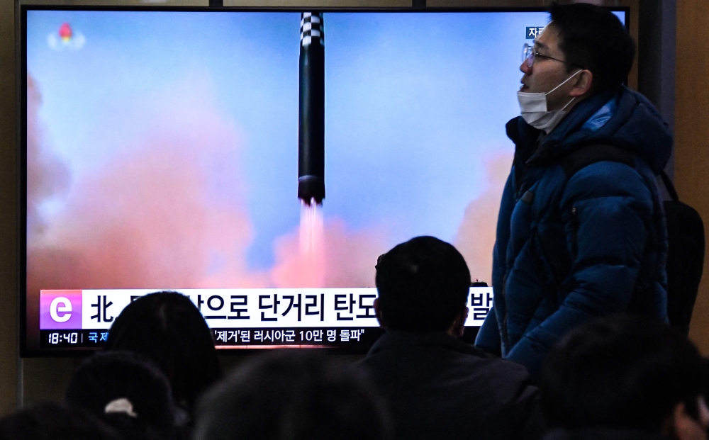 People watch a television screen showing a news broadcast with file footage of a North Korean missile test, at a railway station in Seoul on December 23, 2022 after North Korea fired two short-range ballistic missiles according to South Korea's military. (Photo by Jung Yeon-je / AFP)