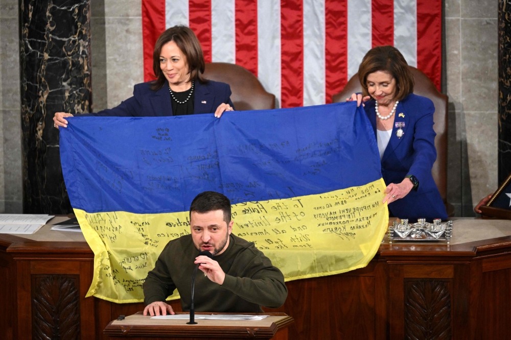 Ukraine's President Volodymyr Zelensky speaks after giving a Ukrainian national flag to US House Speaker Nancy Pelosi and US Vice President Kamala Harris (left) during his address to the US Congress at the US Capitol in Washington, DC on December 21, 2022. (Photo by Mandel Ngan / AFP)

