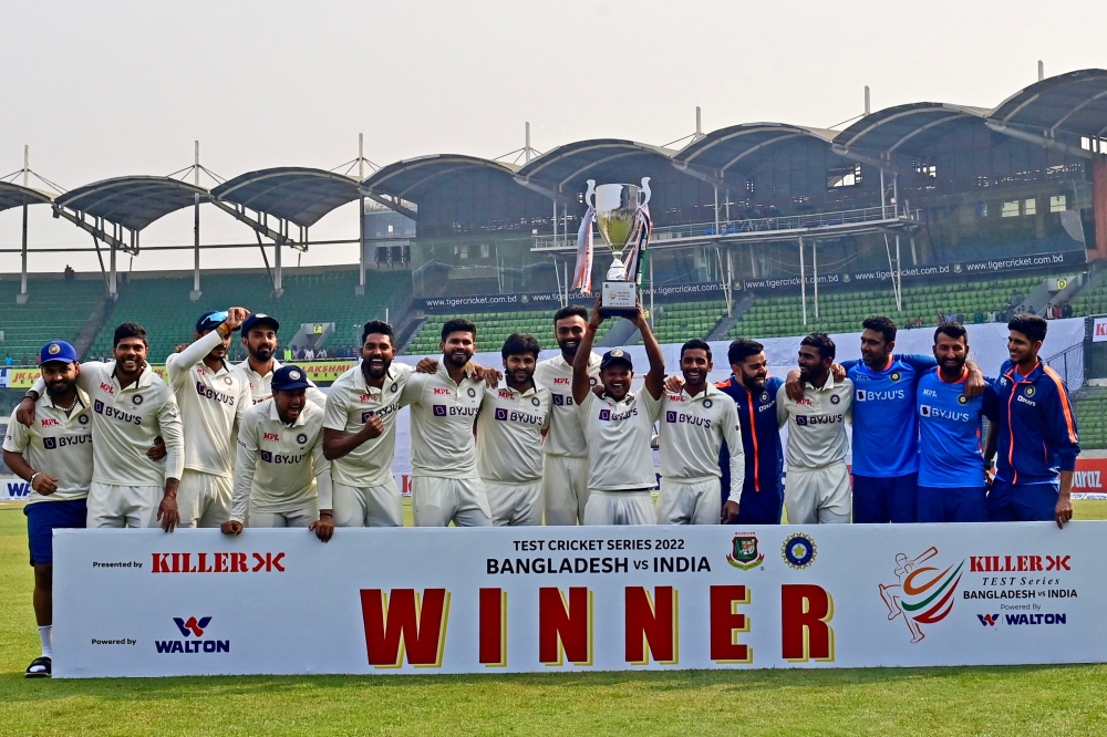 Team India pose as they hold the tournament trophy after winning on the fourth day of the second cricket Test match between Bangladesh and India. (Photo by Munir uz Zaman / AFP)