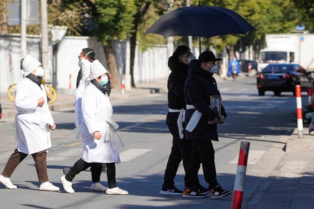 A man wearing a protective mask holds a picture frame of a loved one outside a funeral home, as coronavirus disease (COVID-19) outbreaks continue, in Shanghai, China, on December 23, 2022. REUTERS/Aly Song/File Photo